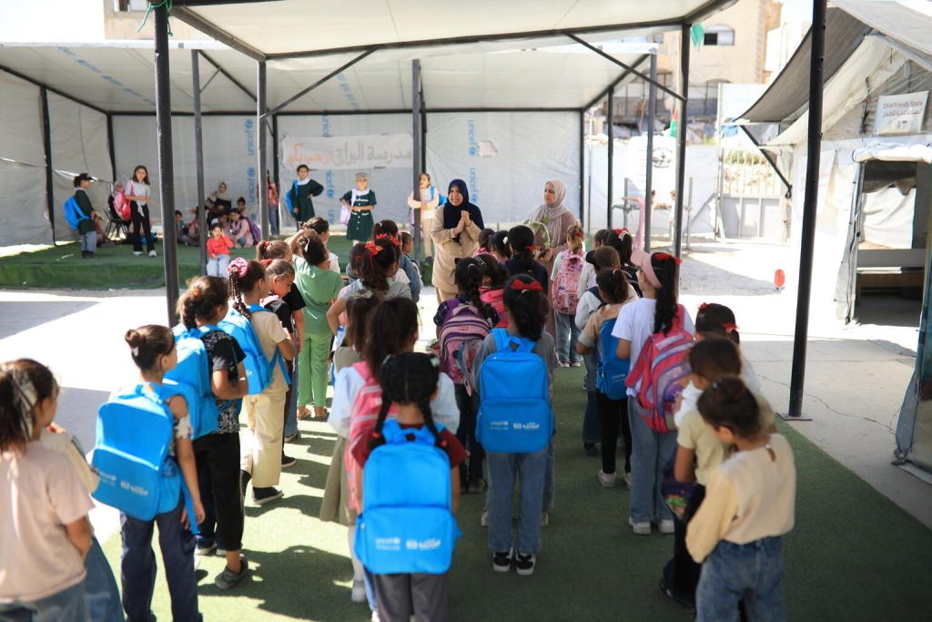 Učenci se z UNICEF-ovimi torbami zbirajo pred učnim prostorom v Gazi.