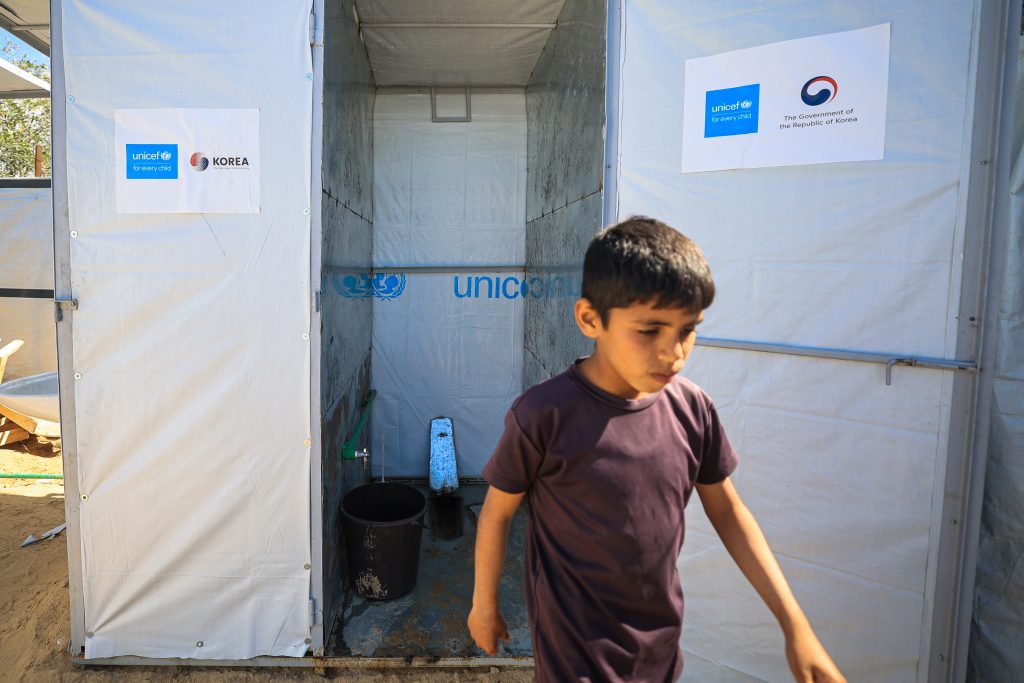 Deček stoji pred sanitarnim objektom v UNICEF-ovem začasnem učnem centru v Gazi.