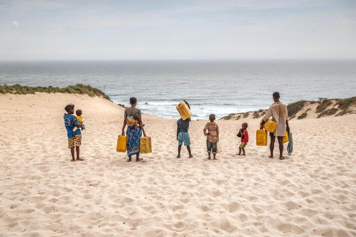 Družina na plaži s posodami za vodo