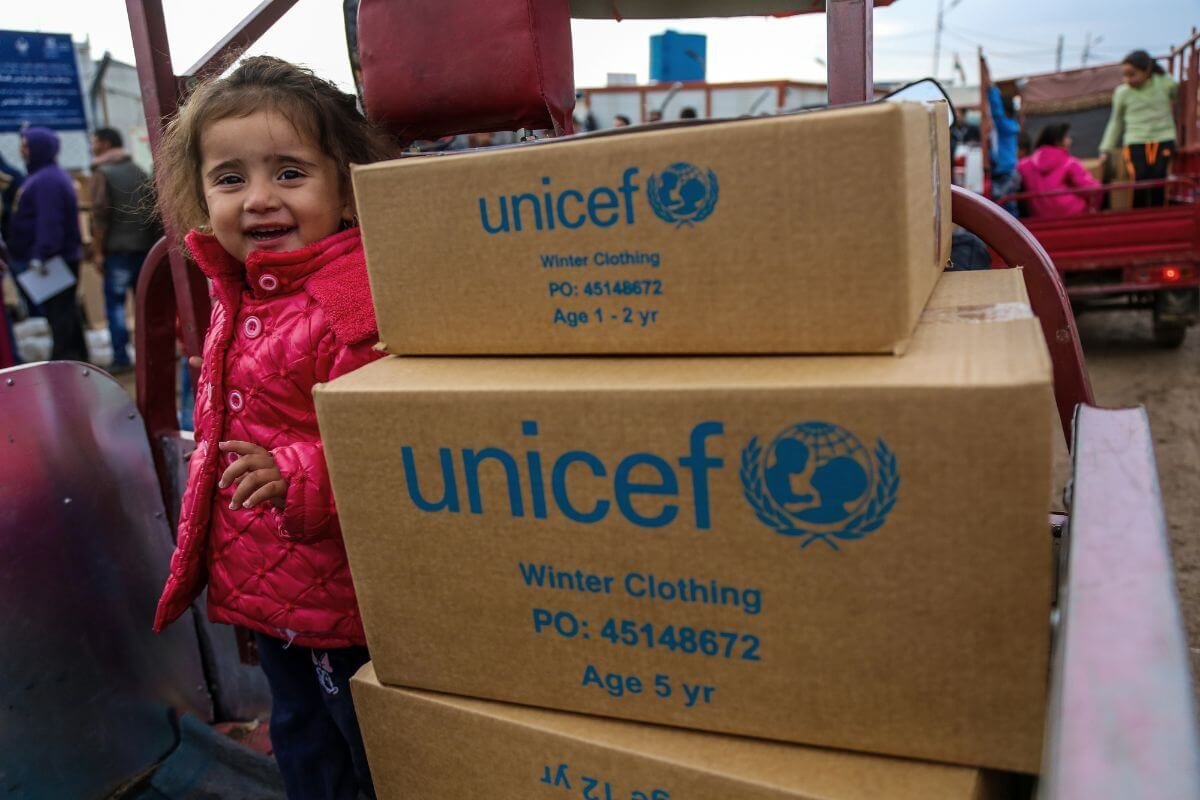 Deklica, ki stoji ob UNICEF-ovih paketih
