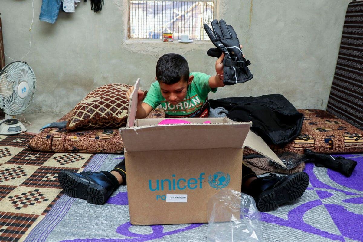 Otrok odpira UNICEF-ov paket z zimsko opremo