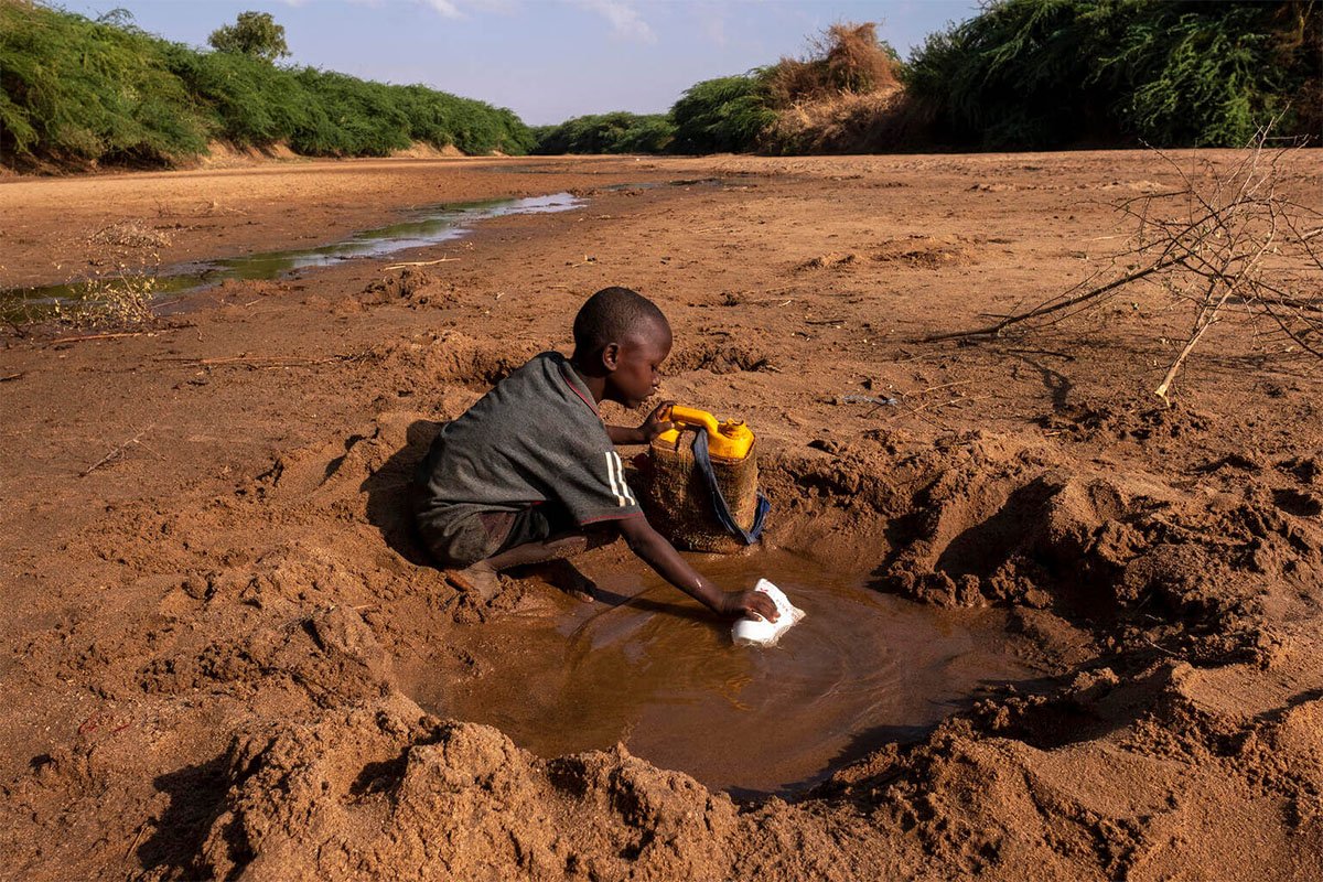 Deček zajema vodo iz posušene reke