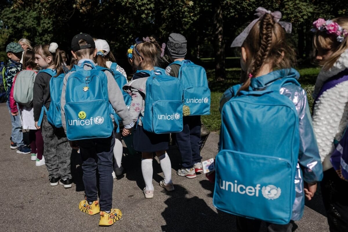 Skupina otrok z modrimi nahrbtniki, na katerih je napis UNICEF.