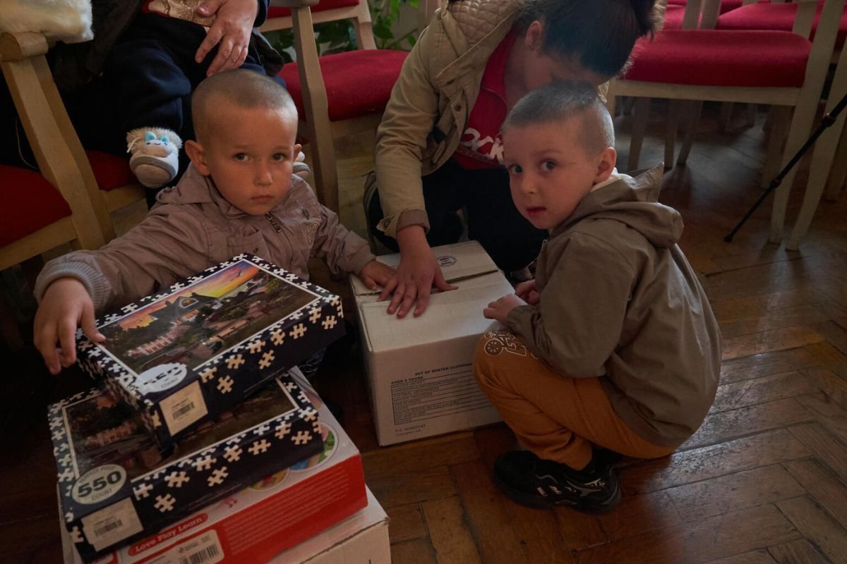 Veseli otroci odpirajo UNICEF-ova darila.