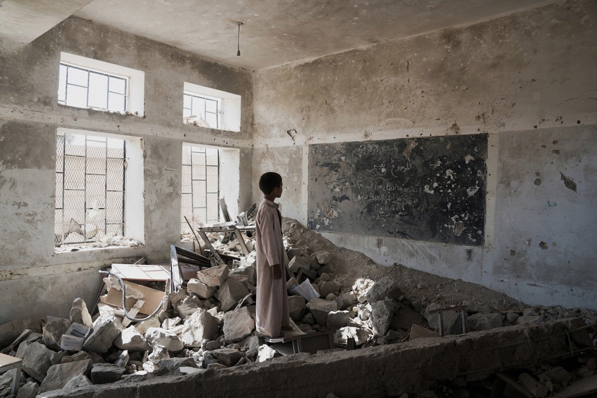 Deček med ruševinami, ki so ostale od učilnice v šoli