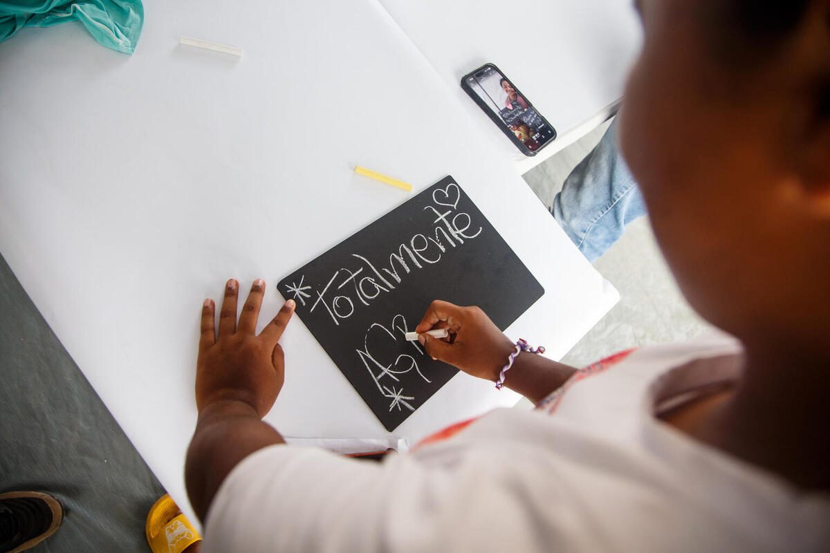 16-letna Gabriela iz Venezuele v UNICEF-ovem varnem prostoru piše na tablo.