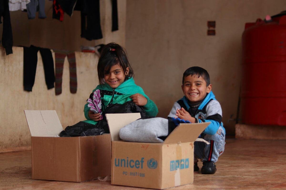 Vesela otroka odpirata UNICEF-ove pakete