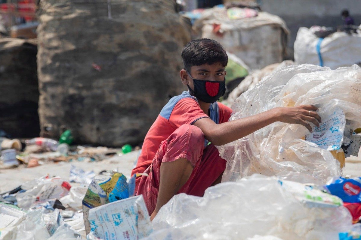 Otrok z masko ločuje plastične odpadke