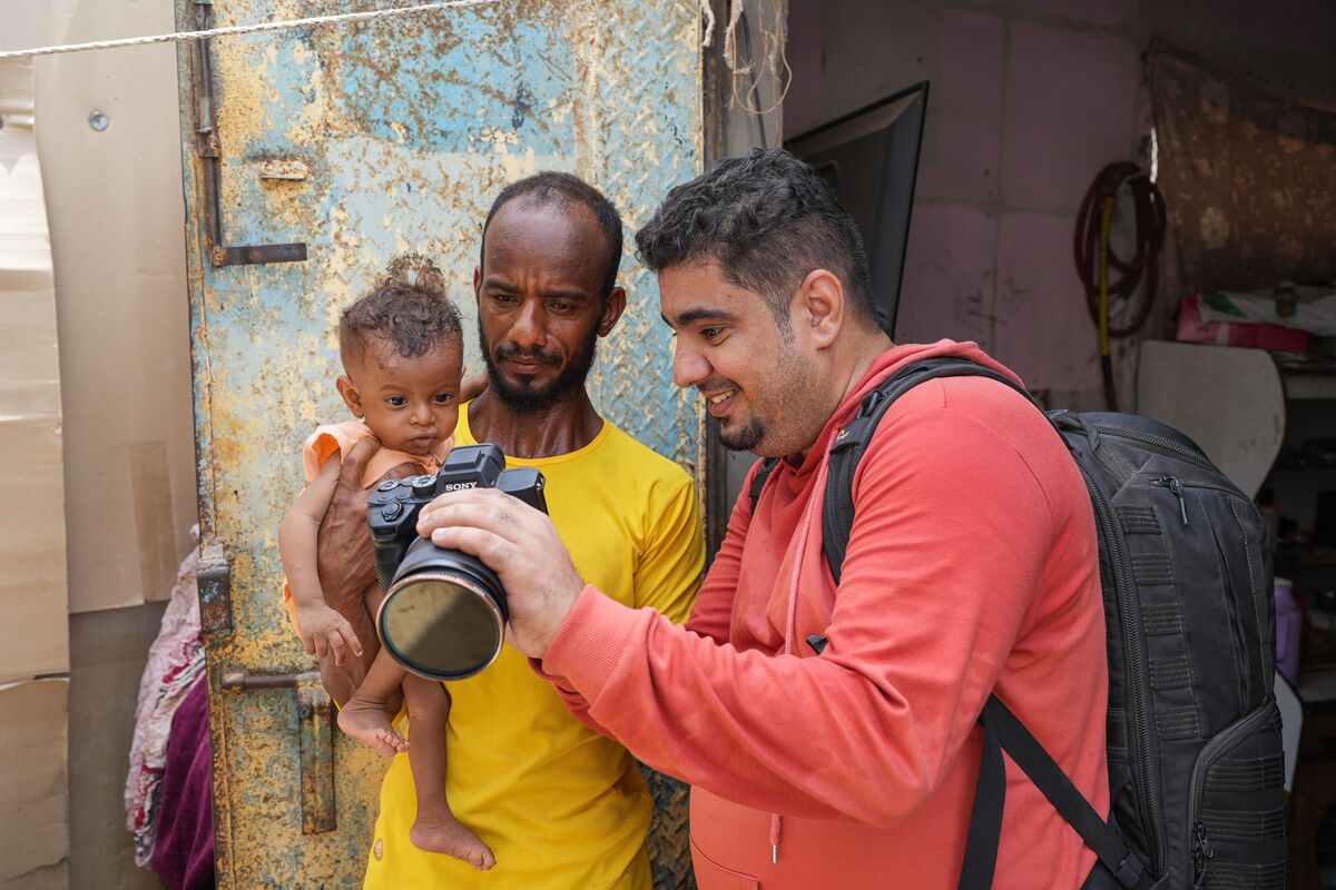 Jemenski fotograf Ala'a Noman Fawazu in njegovemu otroku pokaže fotografijo.