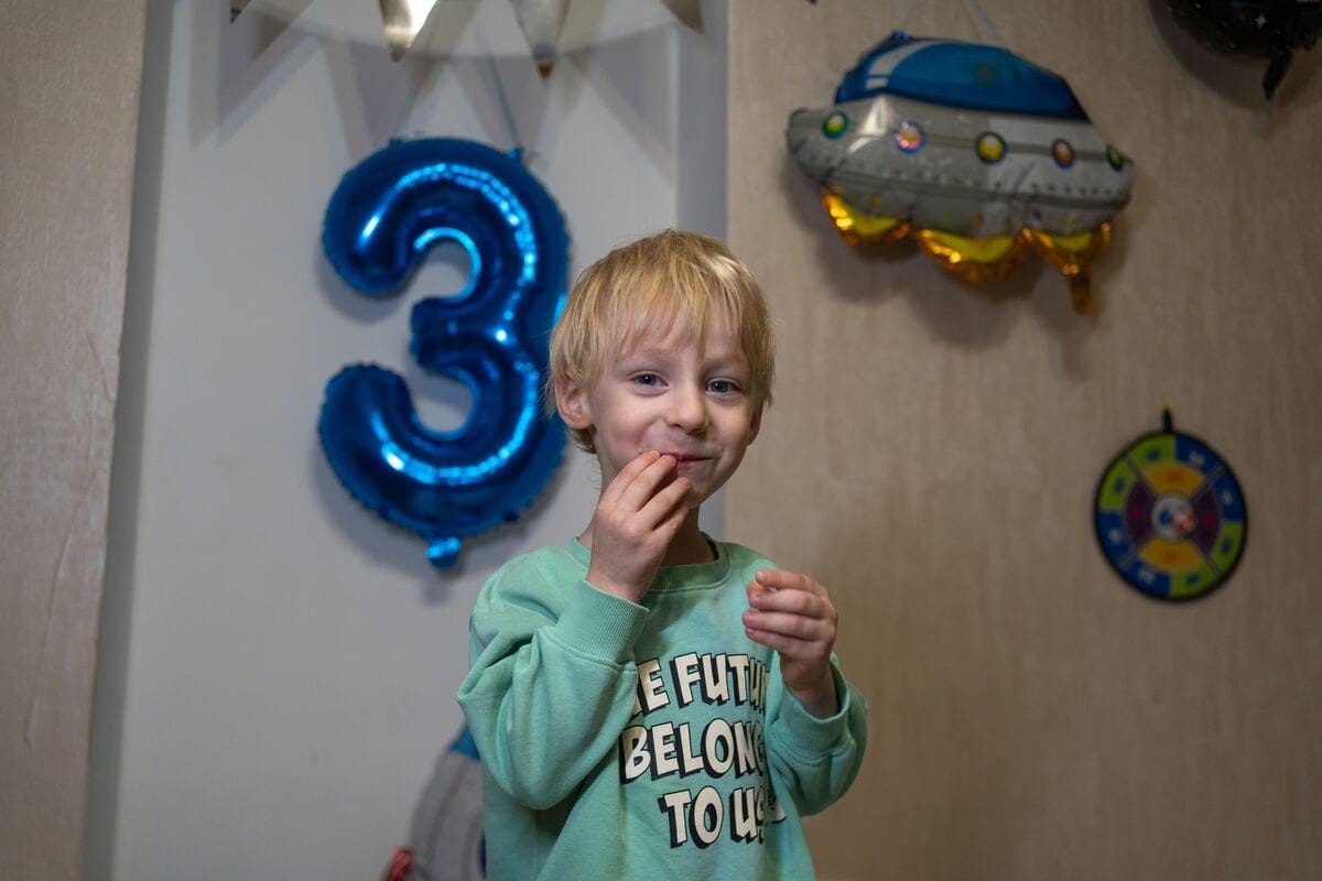 3-letni Jehor iz Ukrajine doma praznuje rojstni dan, ki ga zaznamuje svetlo moder balon v obliki številke 3.