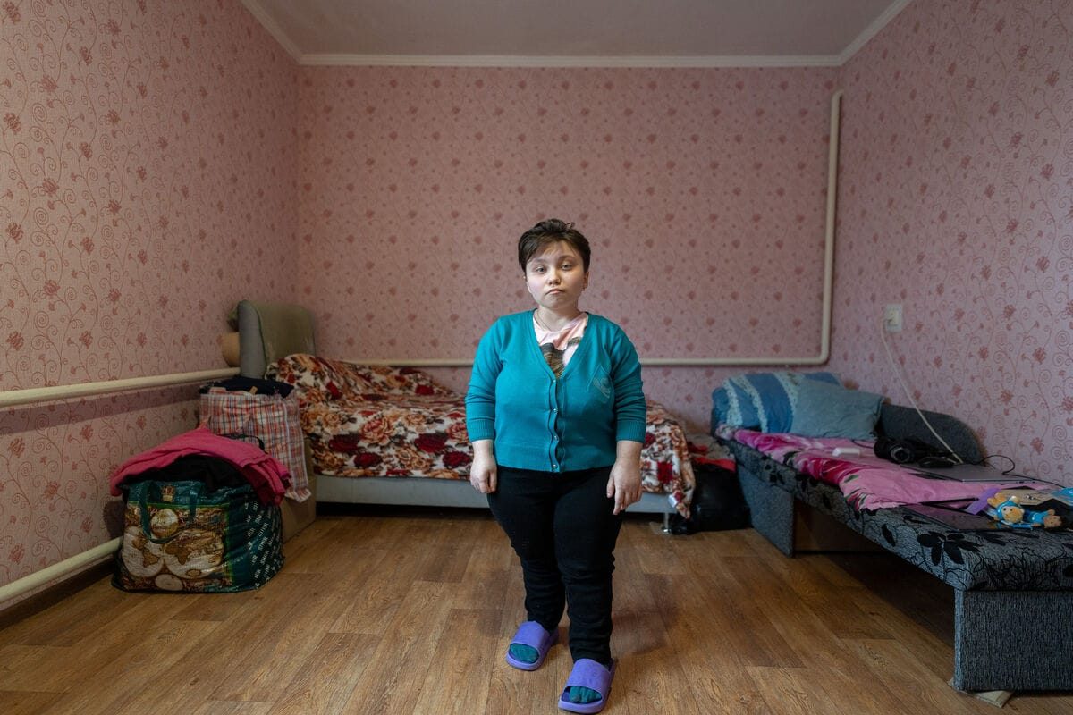 18-letna Darina stoji v svojem majhnem stanovanju v Ukrajini, ki si ga deli s svojima skrbnikoma.