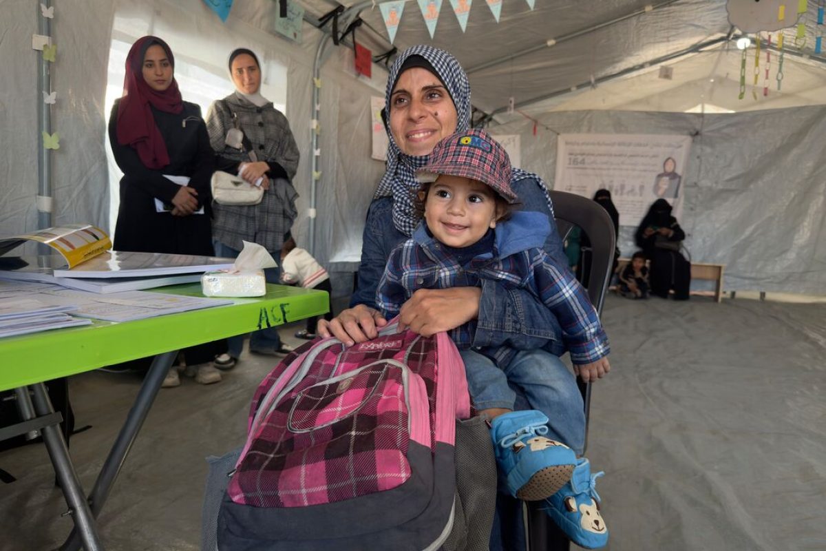 Mati iz Gaze drži otroka, s katerim sta prejela nujno pomoč. Zadovoljna se smejita kameri.