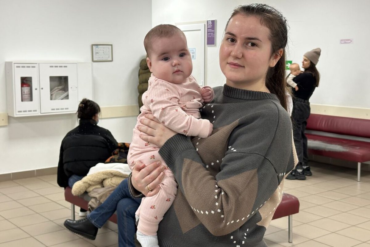 Mati v zdravstvenem centru drži svojo dojenčico in z njo pozira kameri.