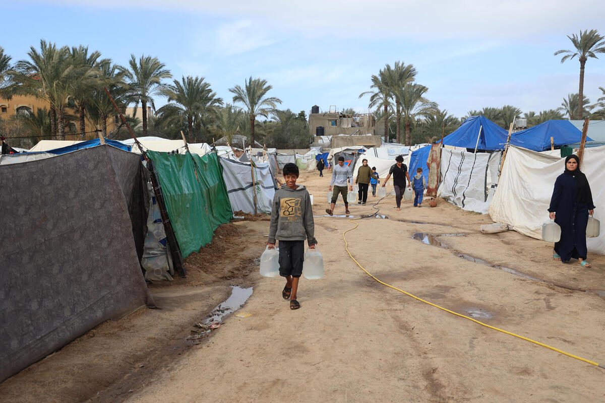 Deček iz Gaze nosi čisto pitno vodo, ki jo je zagotovil UNICEF.